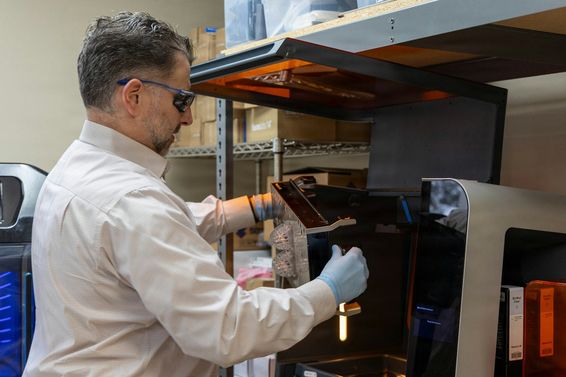 Person wearing gloves operating a 3D printer in a workshop
