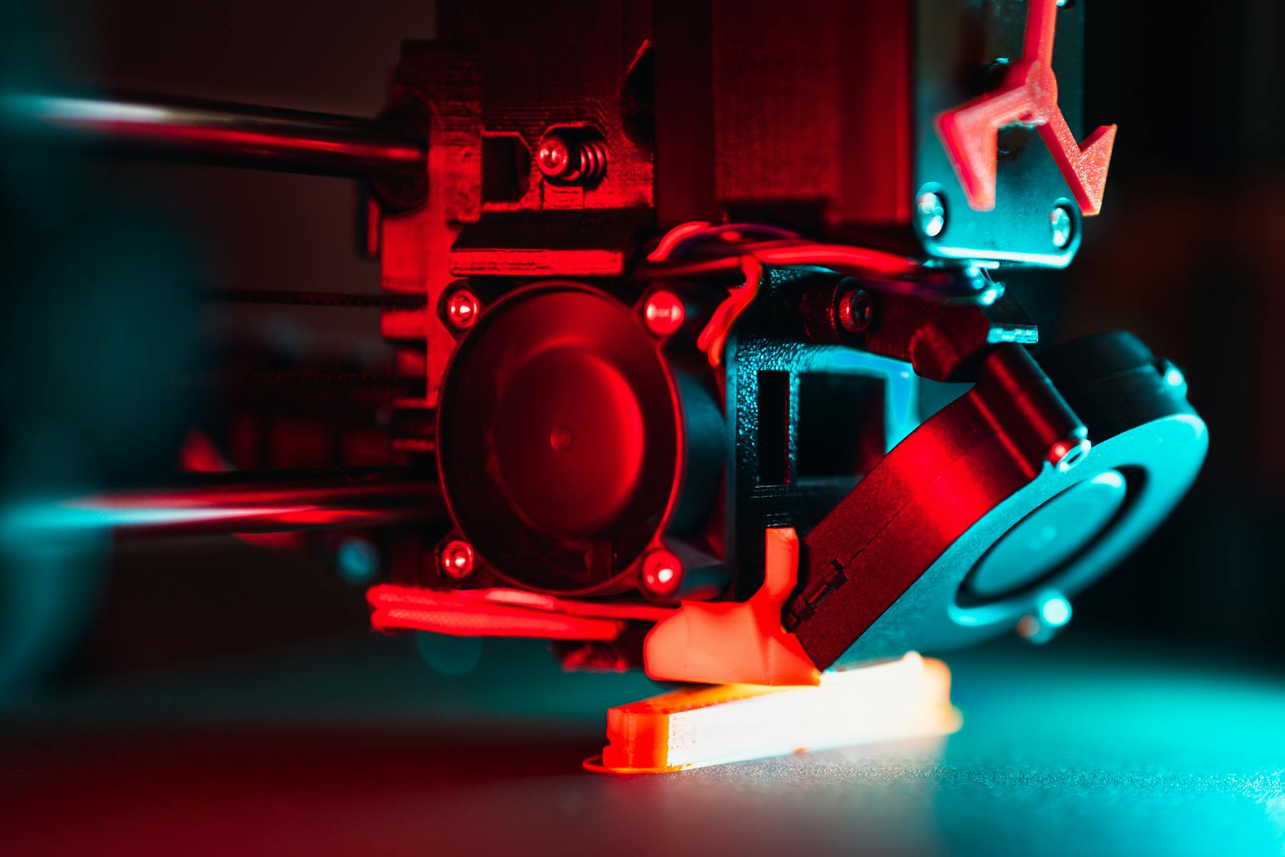 Close-up of a 3D printer printing under coloured workshop lighting